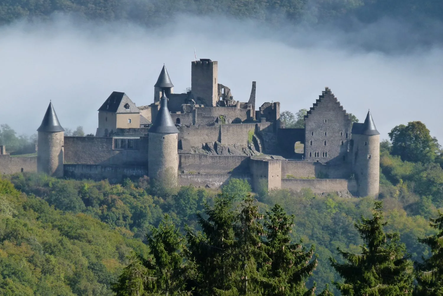 Bourscheid Castle above misty forested hills in Luxembourg